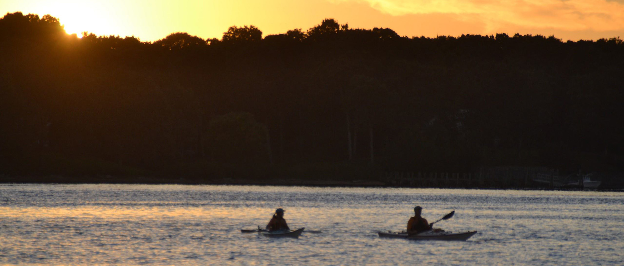 kayakers on river at sunset